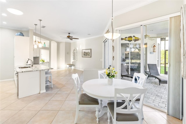 dining space with ceiling fan, light tile patterned floors, crown molding, and sink