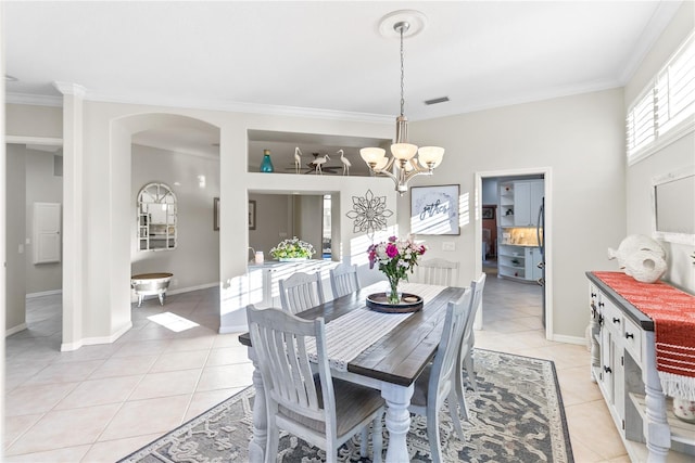 tiled dining area featuring crown molding and a notable chandelier