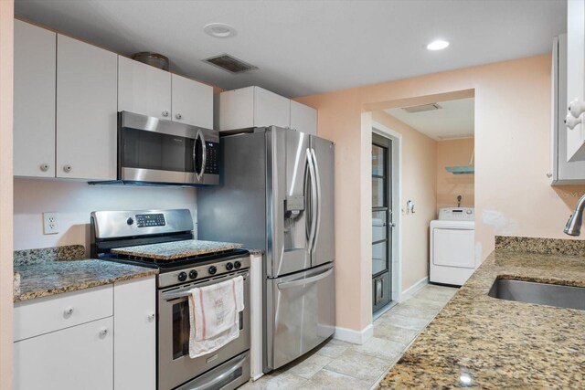 kitchen with light stone counters, washer / dryer, sink, and appliances with stainless steel finishes