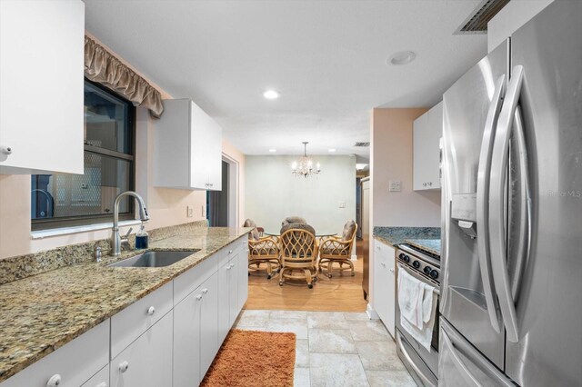 kitchen with white cabinets, an inviting chandelier, appliances with stainless steel finishes, light hardwood / wood-style floors, and sink