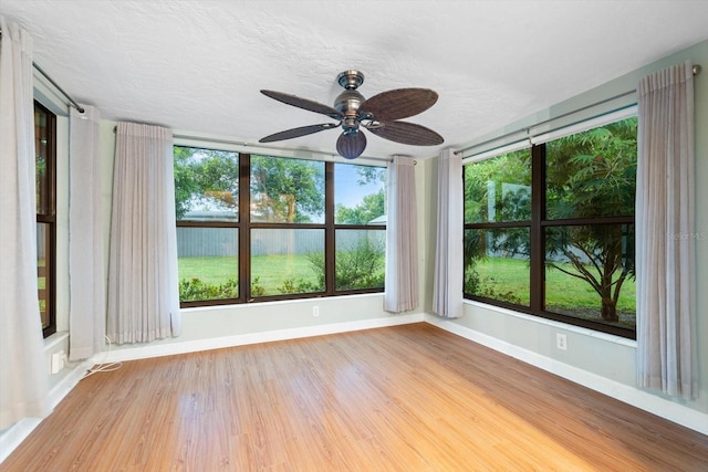 empty room featuring a textured ceiling, plenty of natural light, ceiling fan, and hardwood / wood-style floors