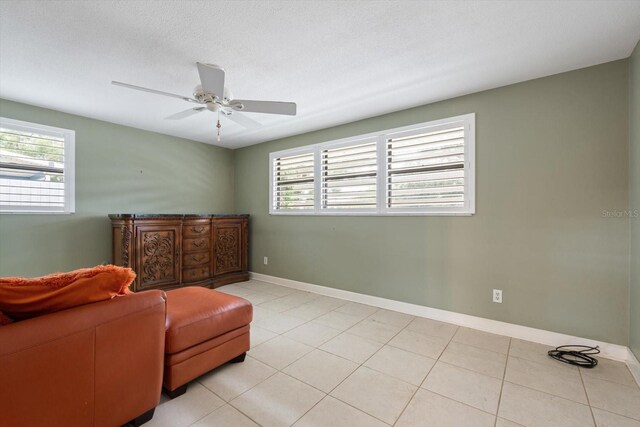 sitting room featuring ceiling fan, light tile patterned flooring, and a textured ceiling