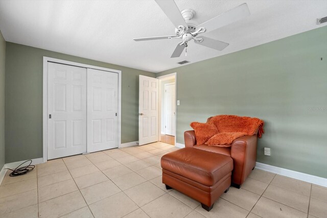 living area featuring ceiling fan, light tile patterned floors, and a textured ceiling