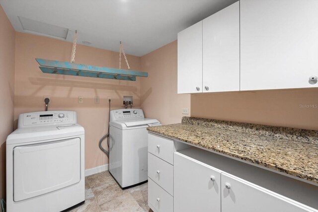 laundry area featuring washing machine and clothes dryer and cabinets