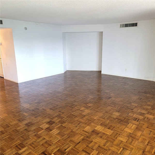 spare room with a textured ceiling and dark parquet flooring