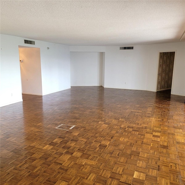 spare room featuring a textured ceiling and dark parquet flooring