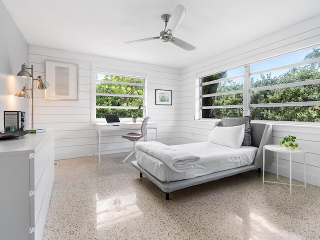 bedroom with ceiling fan and wood walls