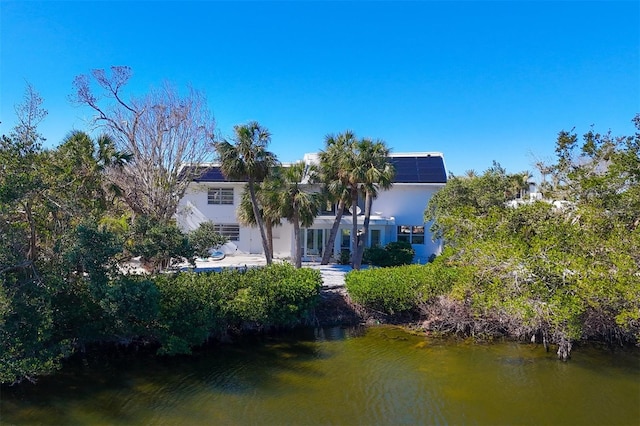 rear view of house with a water view and solar panels