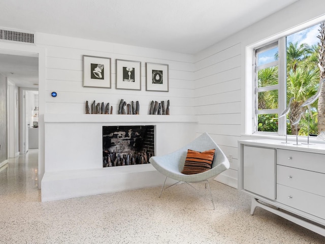 living area featuring wooden walls and a fireplace