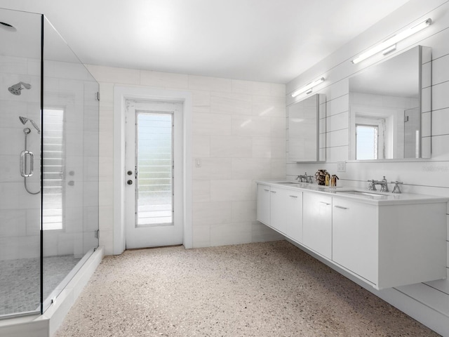 bathroom featuring vanity, tile walls, a healthy amount of sunlight, and walk in shower