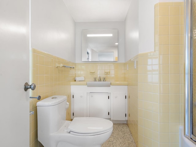 bathroom featuring tile walls, vanity, a shower with door, and toilet