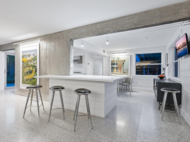 7665 Sanderling Rd, Sarasota, FL 34242 - kitchen with dark aggregate flooring, a breakfast bar, and wall chimney exhaust hood