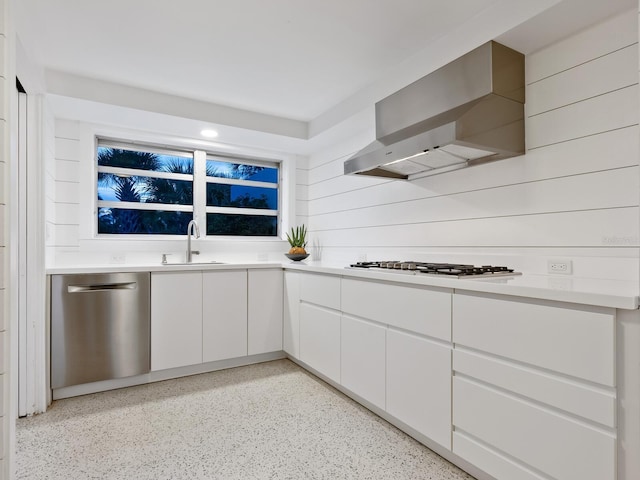 7665 Sanderling Rd, Sarasota, FL 34242 - kitchen with stainless steel dishwasher, gas stovetop, wall chimney range hood, wooden walls, and white cabinets