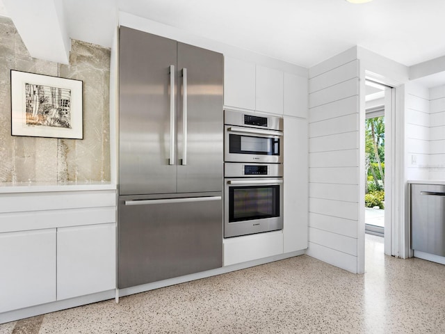7665 Sanderling Rd, Sarasota, FL 34242 - kitchen featuring appliances with stainless steel finishes, dark speckled floor, white cabinetry, and light countertops
