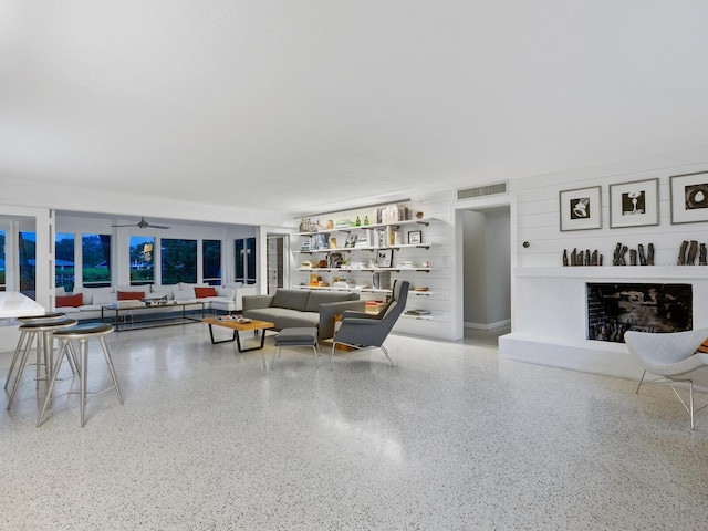 7665 Sanderling Rd, Sarasota, FL 34242 - living area featuring speckle patterned floor, a fireplace with raised hearth, and a ceiling fan