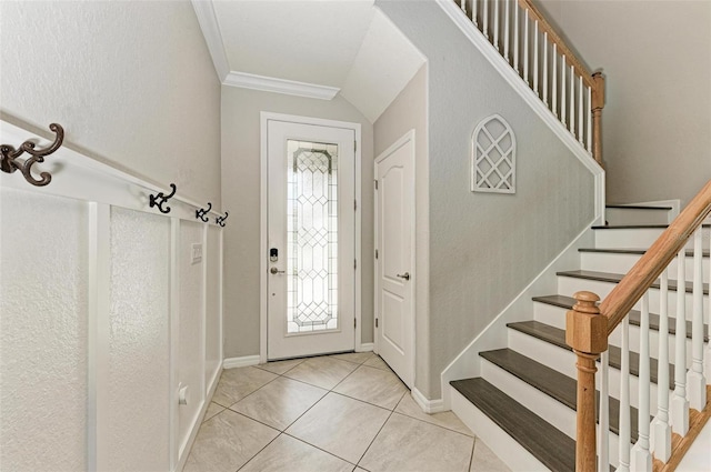 tiled entryway featuring vaulted ceiling and ornamental molding