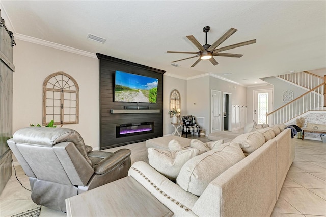 tiled living room featuring a large fireplace, ceiling fan, and ornamental molding