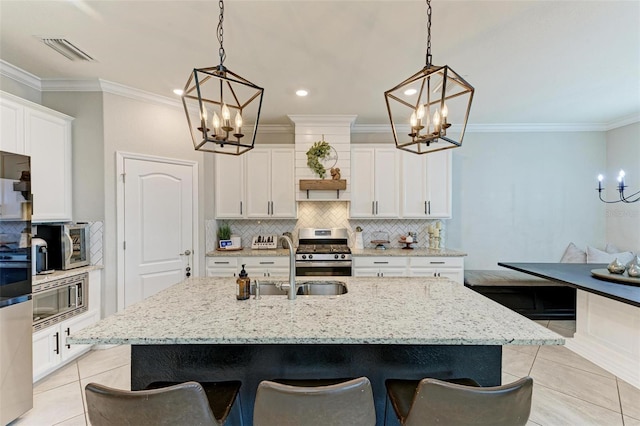 kitchen with appliances with stainless steel finishes, an island with sink, a breakfast bar area, and light tile patterned floors