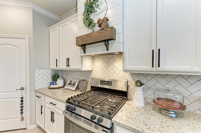 kitchen featuring gas range, light stone countertops, tasteful backsplash, crown molding, and white cabinets