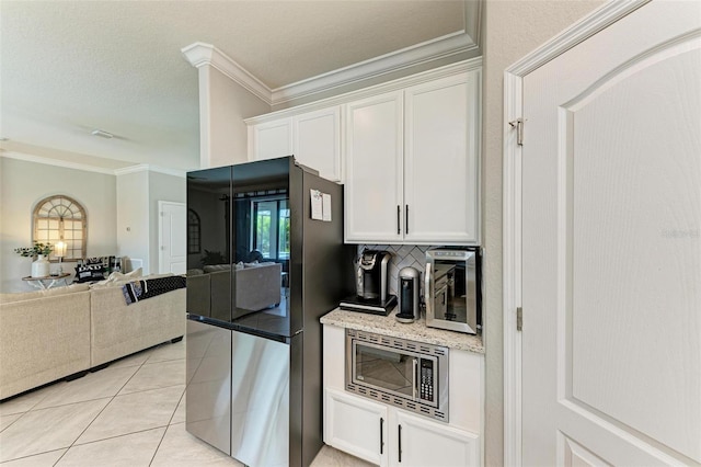 kitchen featuring ornamental molding, white cabinetry, decorative backsplash, stainless steel microwave, and black fridge