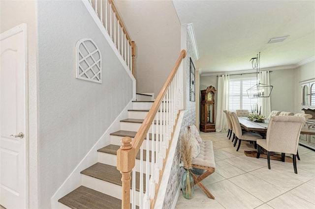 stairs with ornamental molding, a notable chandelier, and tile patterned flooring