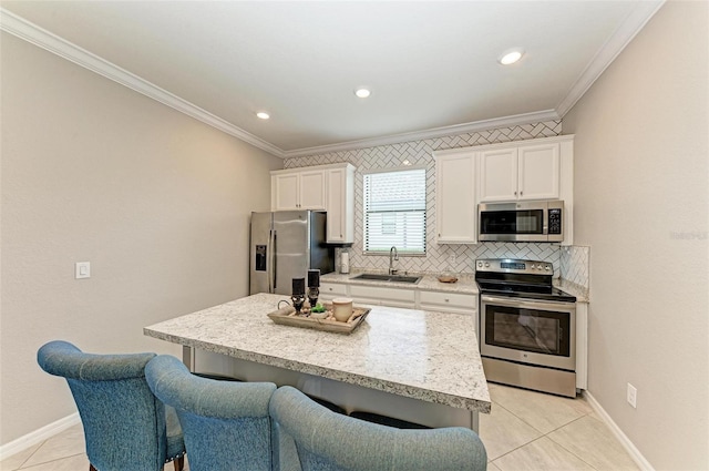 kitchen with stainless steel appliances, white cabinetry, sink, a kitchen island, and a breakfast bar