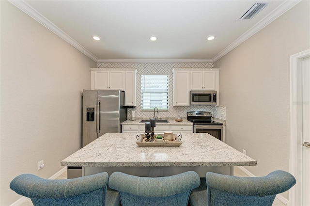 kitchen with tasteful backsplash, stainless steel appliances, a kitchen breakfast bar, a kitchen island, and white cabinets