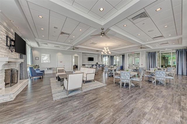 living room featuring a large fireplace, a healthy amount of sunlight, ceiling fan with notable chandelier, and wood-type flooring