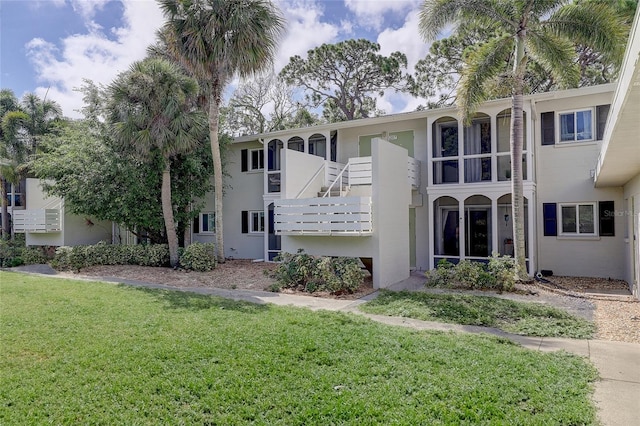 view of front facade featuring a balcony and a front yard