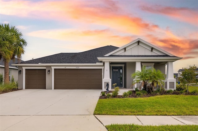 view of front of home with a garage, a porch, and a lawn