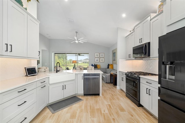 kitchen featuring vaulted ceiling, black appliances, light hardwood / wood-style flooring, backsplash, and sink