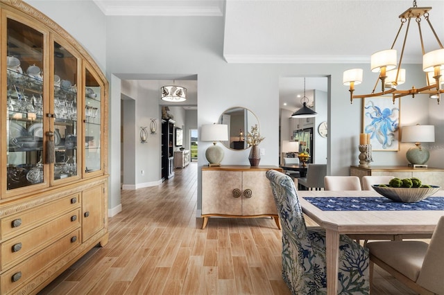 dining area featuring crown molding, an inviting chandelier, and light hardwood / wood-style floors