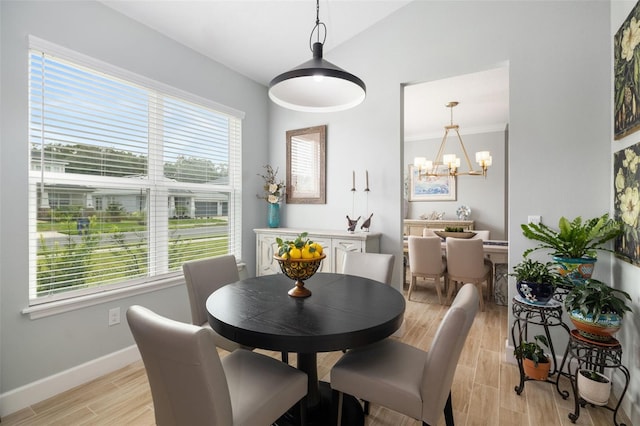 dining area with lofted ceiling, a notable chandelier, and light hardwood / wood-style floors