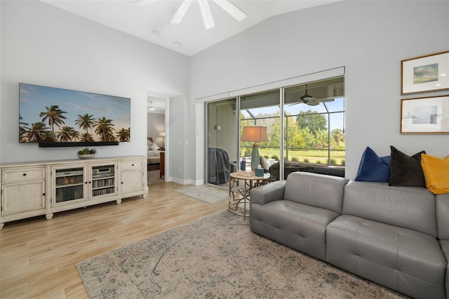 living room with ceiling fan, vaulted ceiling, and light hardwood / wood-style floors