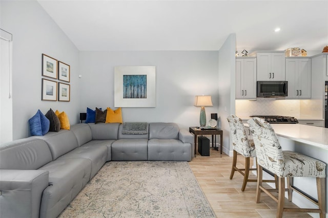 living room with vaulted ceiling and light wood-type flooring