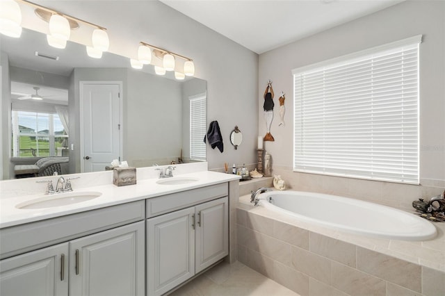 bathroom featuring tile patterned flooring, a relaxing tiled tub, and vanity