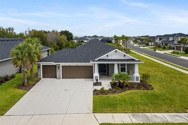 view of front facade featuring covered porch, a front yard, and a garage