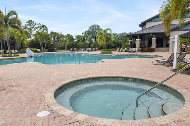 view of swimming pool featuring a hot tub and a patio