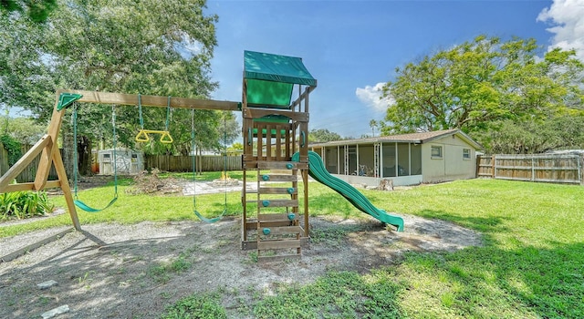 view of playground with a lawn, a sunroom, and a storage shed