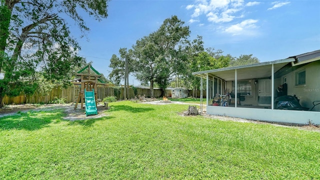 view of yard featuring a storage unit, a sunroom, and a playground