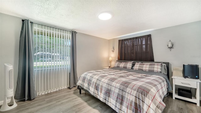 bedroom with a textured ceiling and light hardwood / wood-style flooring