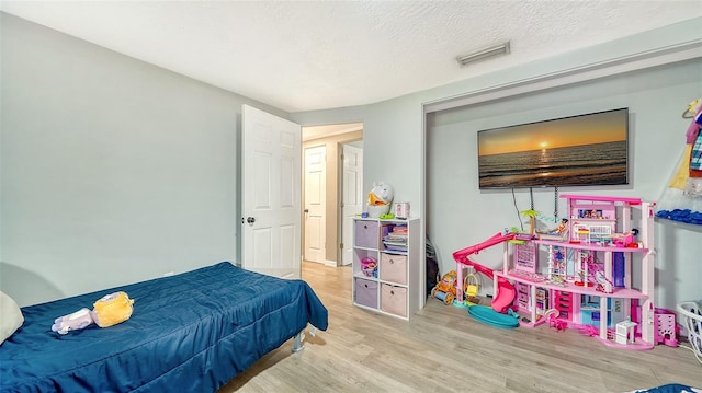 bedroom with light hardwood / wood-style floors and a textured ceiling