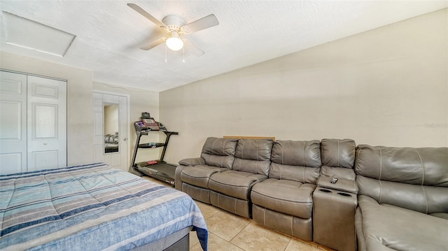 tiled bedroom with a textured ceiling, ceiling fan, and a closet