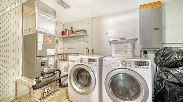 laundry room featuring electric water heater, a textured ceiling, washer and clothes dryer, and electric panel