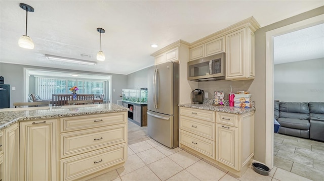 kitchen with pendant lighting, light tile patterned floors, light stone countertops, cream cabinets, and appliances with stainless steel finishes