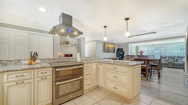 kitchen featuring light hardwood / wood-style floors, light stone counters, stainless steel range with electric stovetop, and island exhaust hood