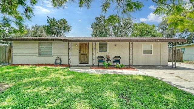 ranch-style home featuring covered porch and a front lawn