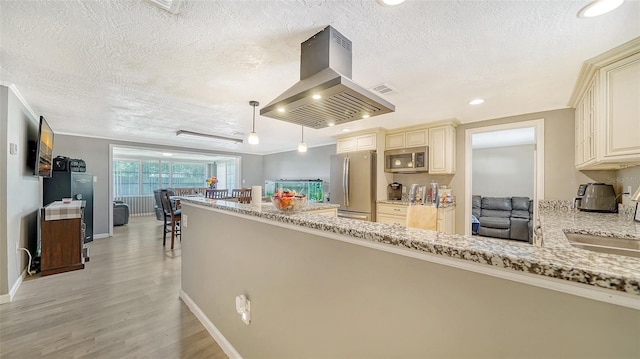 kitchen with decorative light fixtures, light stone countertops, stainless steel appliances, island exhaust hood, and cream cabinetry