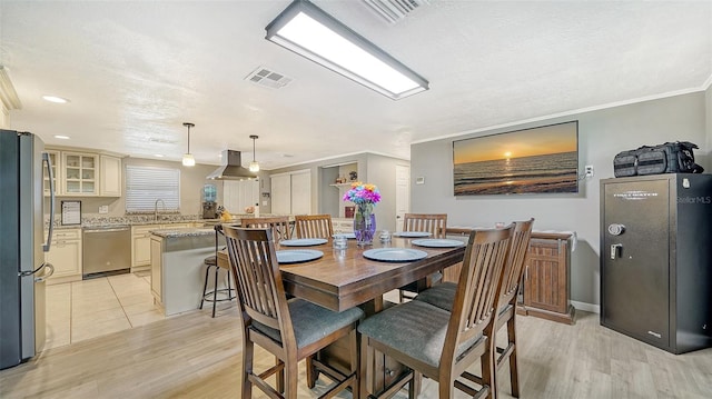 dining room featuring a textured ceiling, ornamental molding, and light wood-type flooring