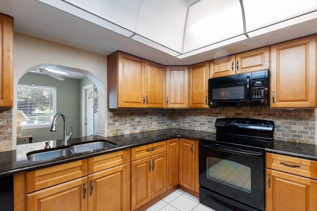 kitchen featuring ceiling fan, sink, tasteful backsplash, dark stone counters, and black appliances